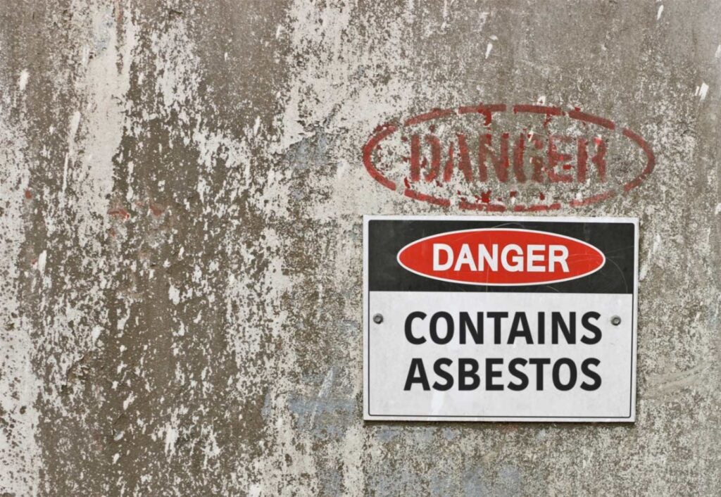 Wall with a sign that says "Danger Contains Asbestos"