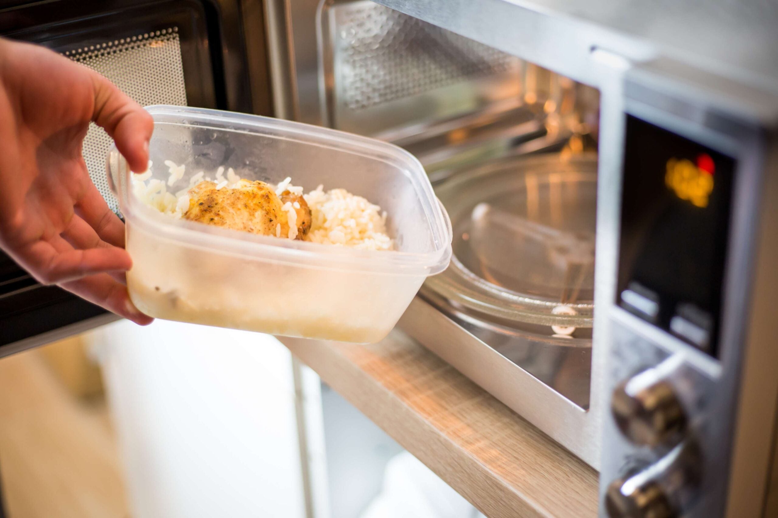 Plastic container of food on its way into a microwave