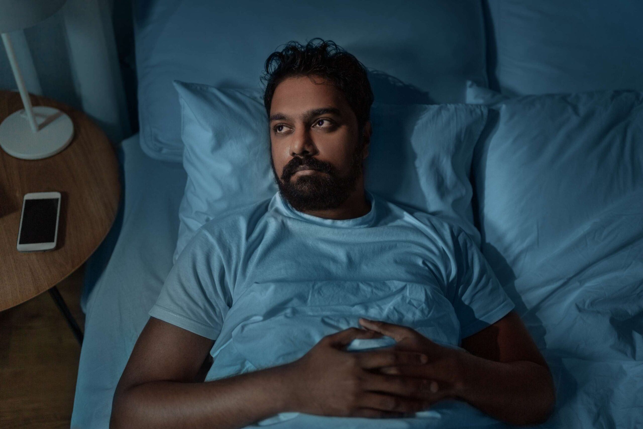 Person lying awake in bed in darkened room