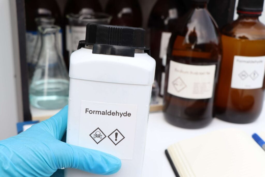 A gloved hand taking a bottle labeled "Formaldehyde"