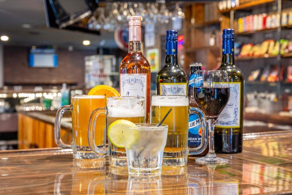Different kinds of alcoholic beverages sitting on the bar at a pub.