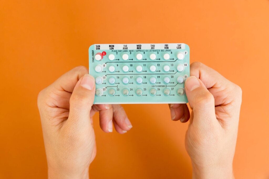 Two hands holding up a pack of birth control pills
