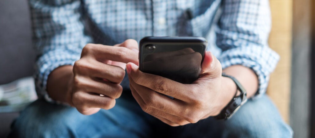 Torso and hands of white man using a cell phone