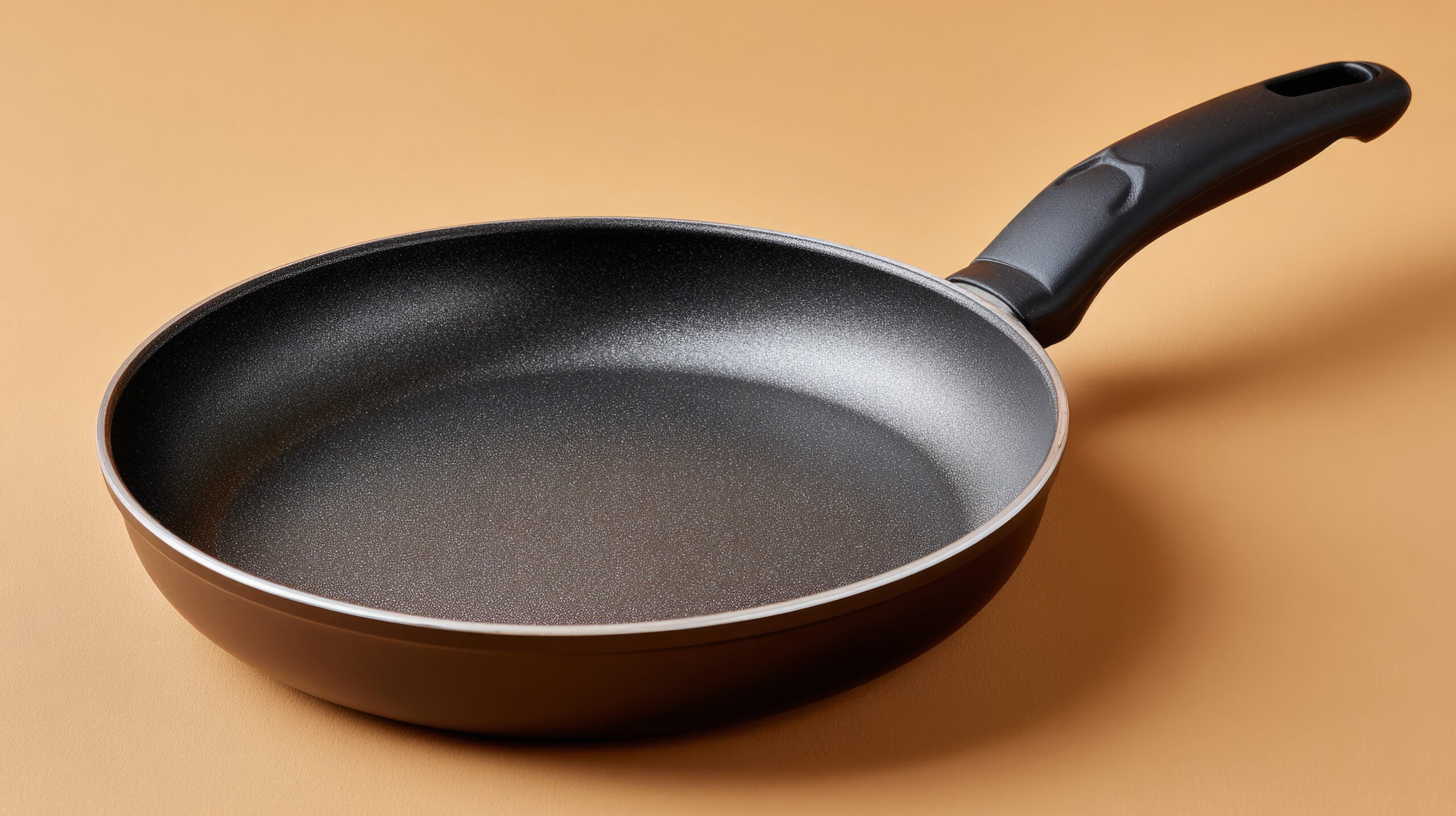 Non-stick frying pan isolated on beige background