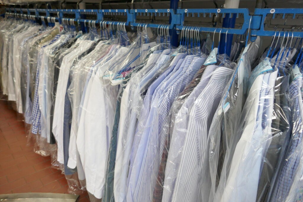 Photo of dry cleaned shirts in plastic on a rack.
