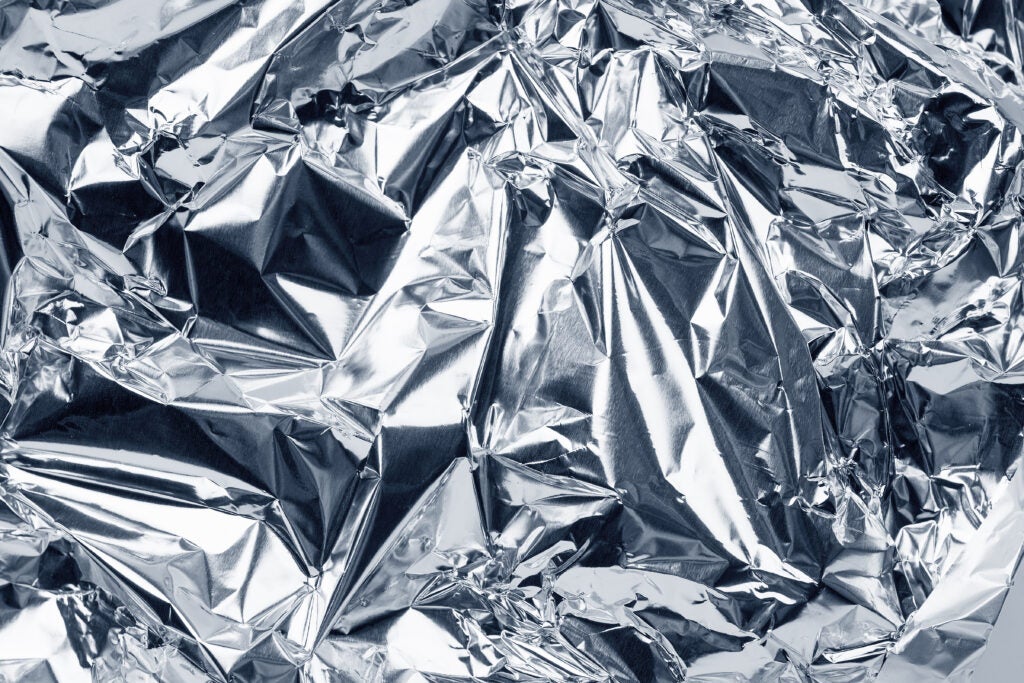 sheet of silver leaf aluminum foil background with shiny crumpled uneven surface