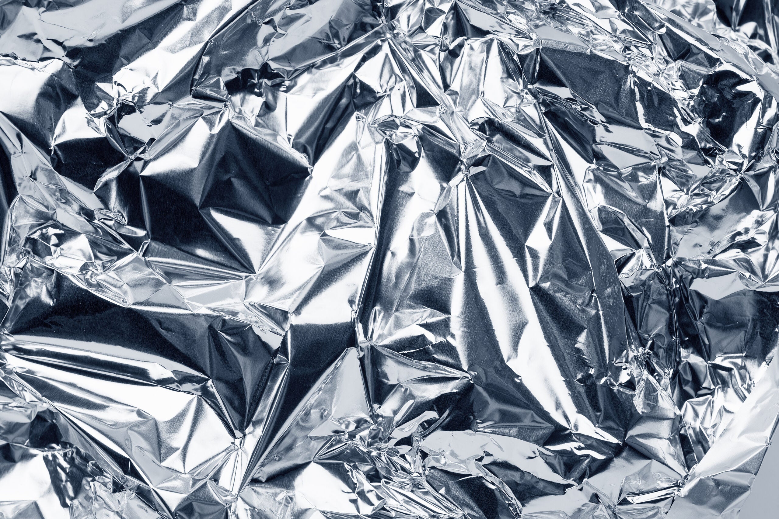 sheet of silver leaf aluminum foil background with shiny crumpled uneven surface
