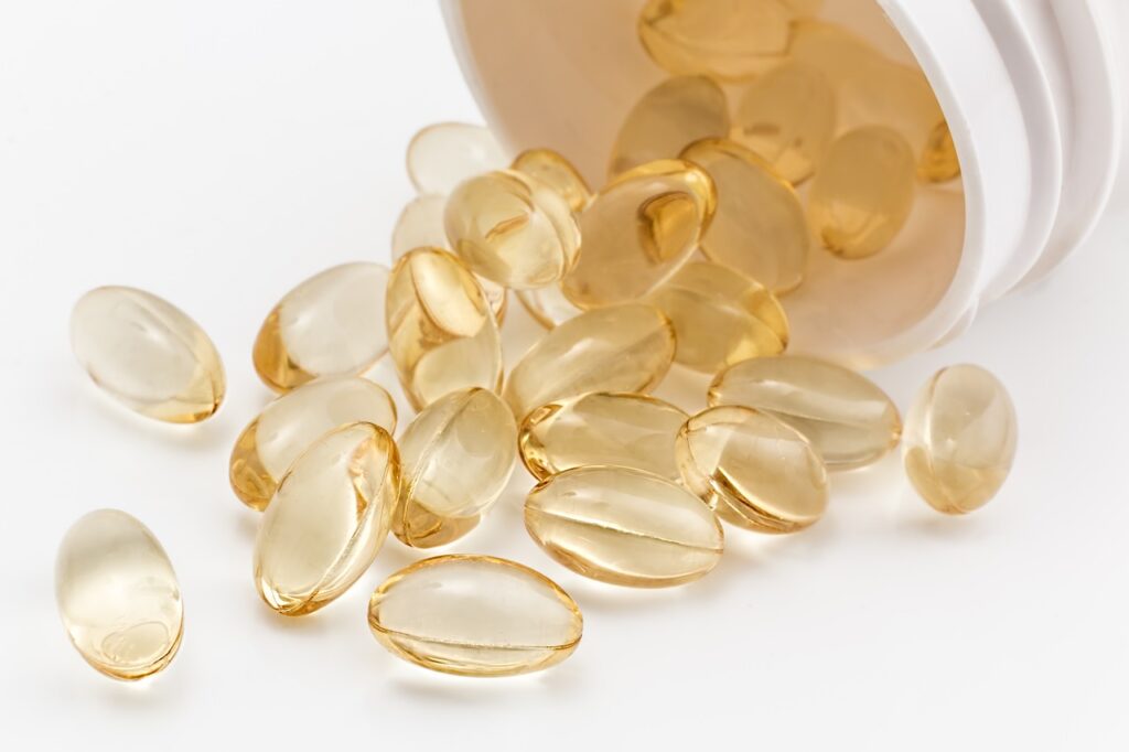 Vitamin D gel tablets spilling out of a white bottle