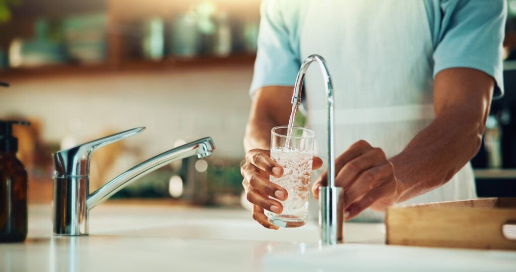 Person filling up a glass of water at the kitchen sink