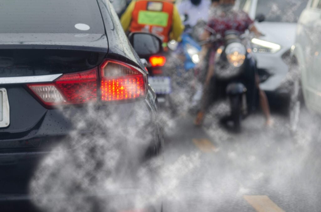 Cars and motorcycles in traffic and exhaust.