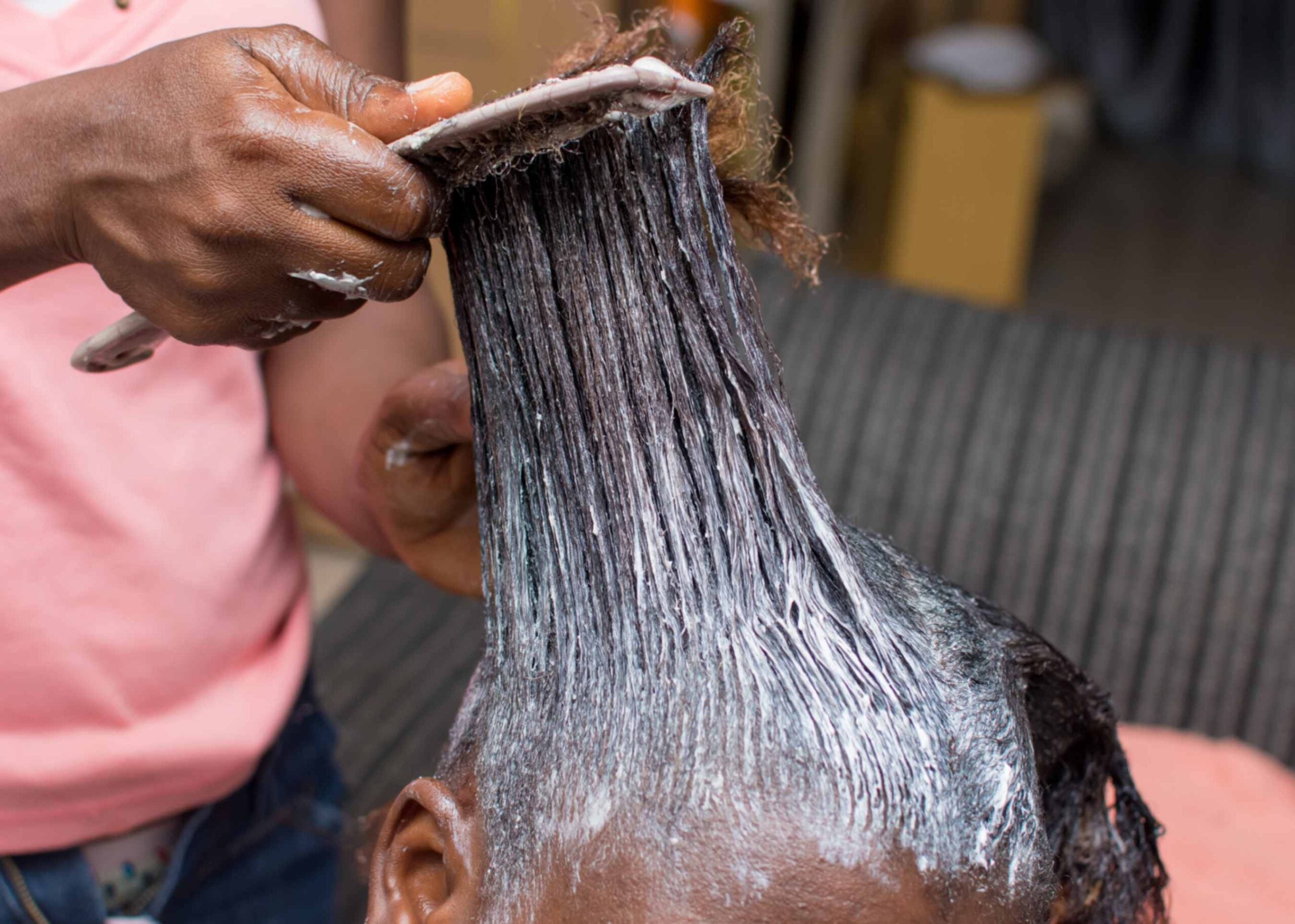 Person at a hair salon getting a chemical combed through their hair