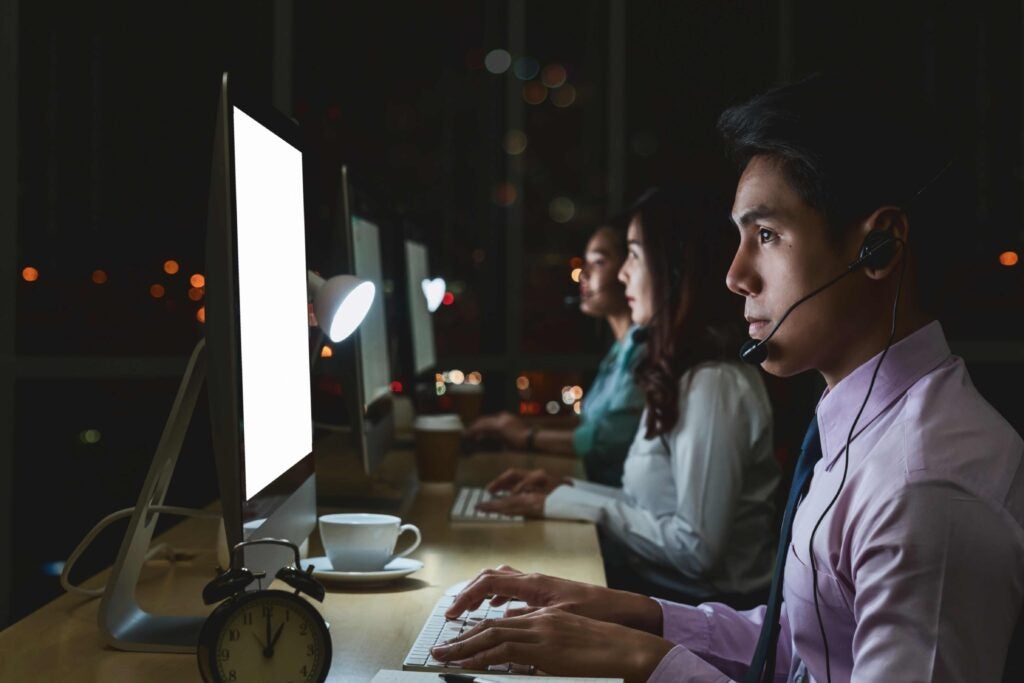 Customer service worker at a computer staring into a screen at night