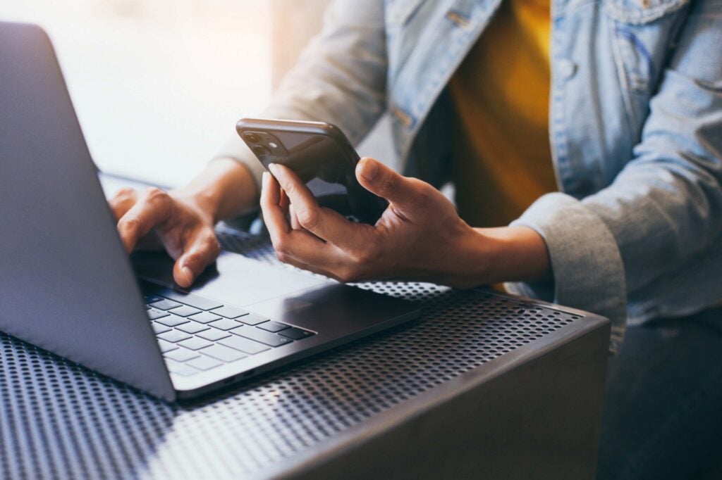 Person using a cell phone and a laptop