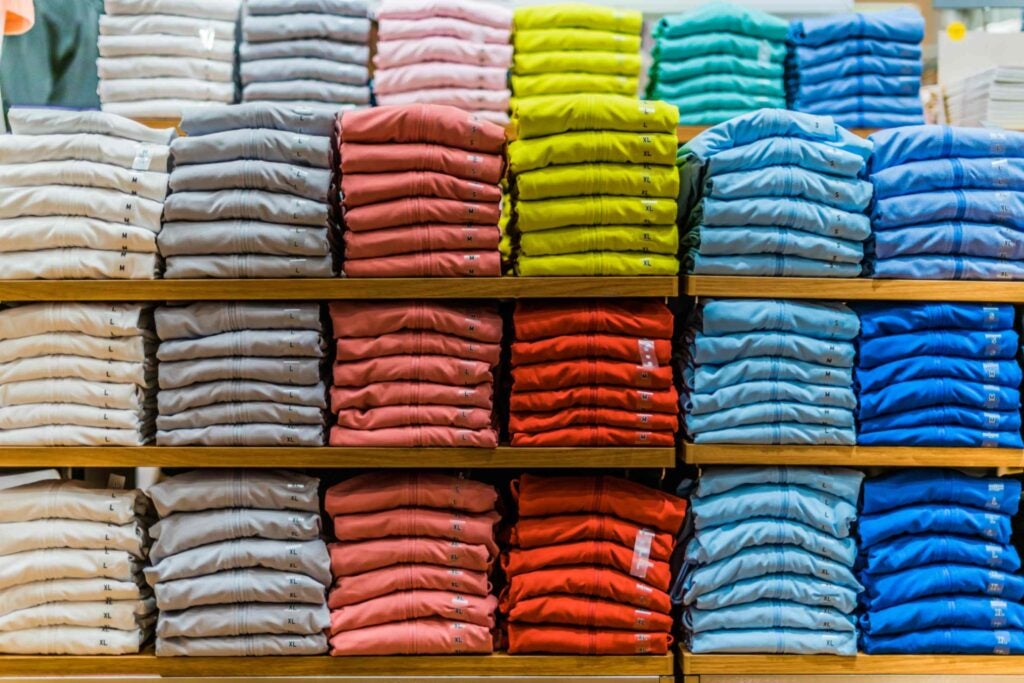 Different color shirts folded and stacked on a shelf in a store.